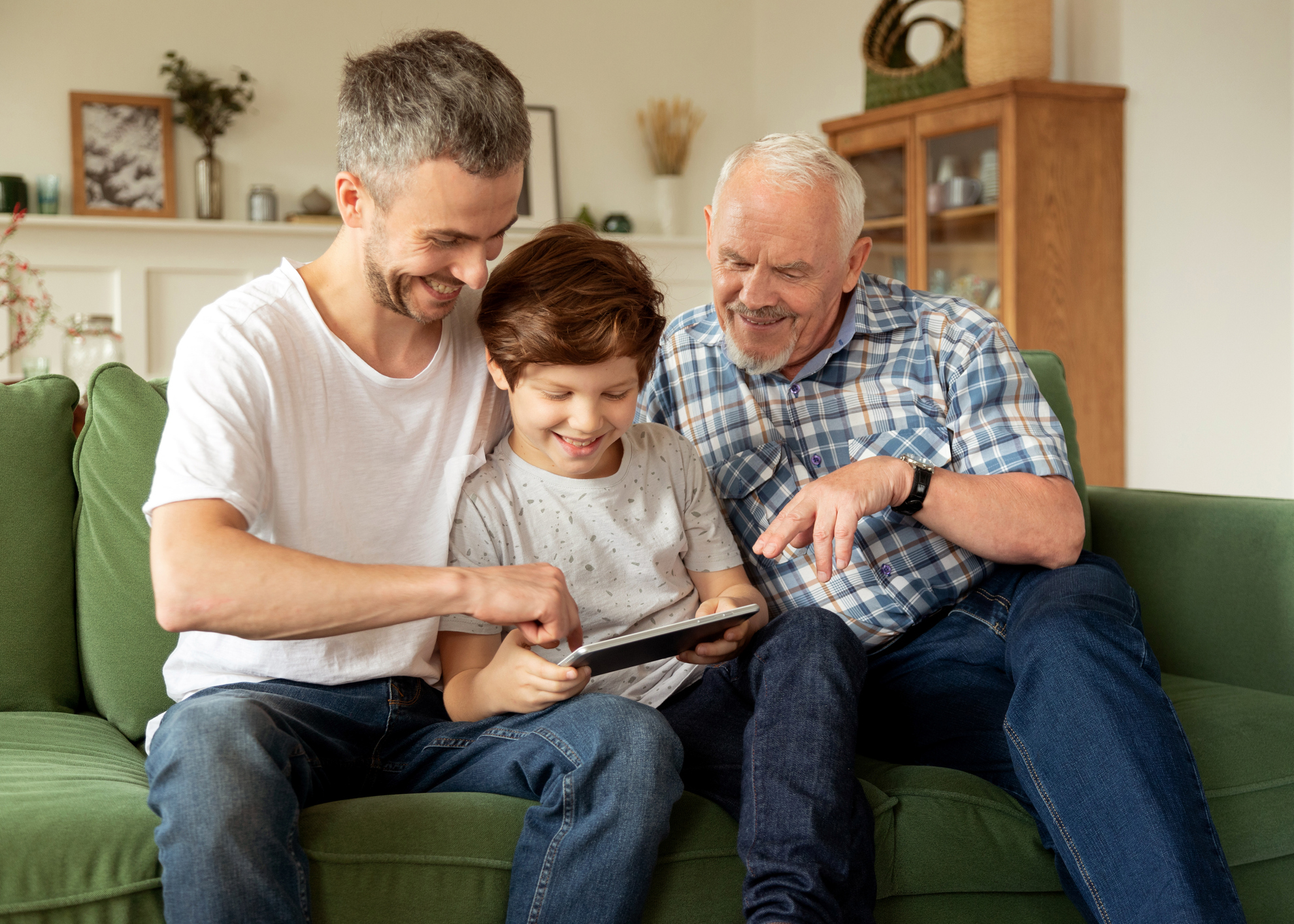 Male members of multi generation family using digital tablet together at home